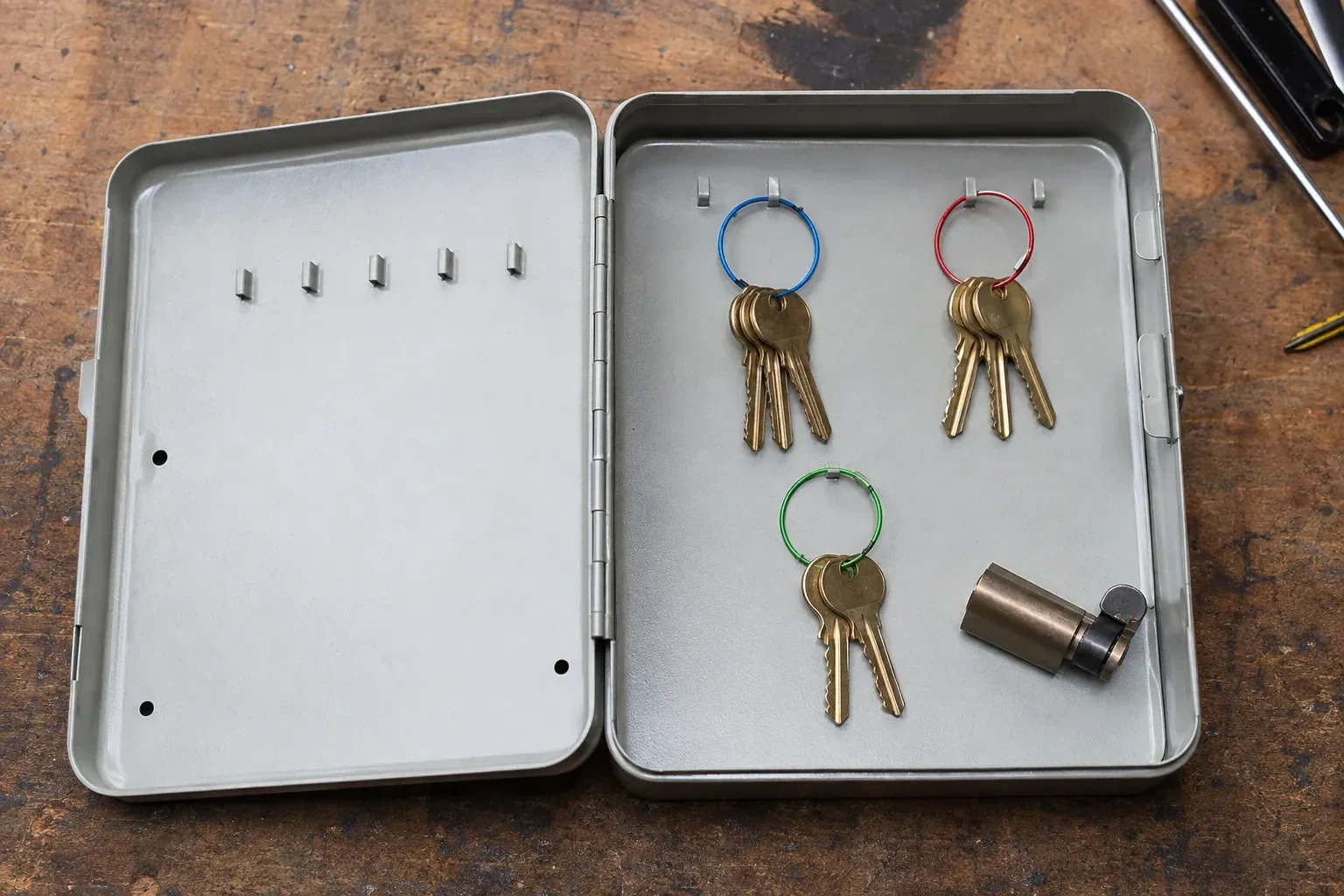 Three groups of keys on colored rings in an open metal key cabinet. — Master Key System Design, Ajax